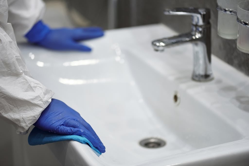 Person in Latex Gloves Cleaning Washbasin